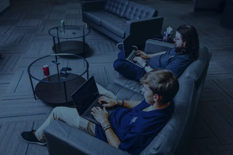 People working on laptops in a modern lobby illustrating IT solutions and support.